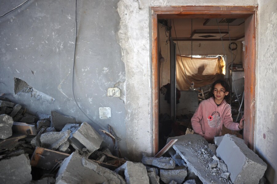 Una ragazza si trova all’interno di un edificio distrutto a seguito di un attacco aereo israeliano sul campo di Bureij per i rifugiati palestinesi nella Striscia di Gaza centrale. (Eyad BABA / AFP)
