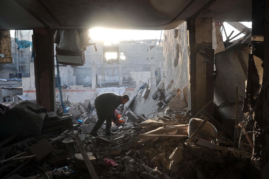 Un uomo siede accanto alle sue cose recuperate dalle macerie di un edificio distrutto in seguito a un attacco aereo israeliano sul campo di Bureij. ( Eyad BABA / AFP)