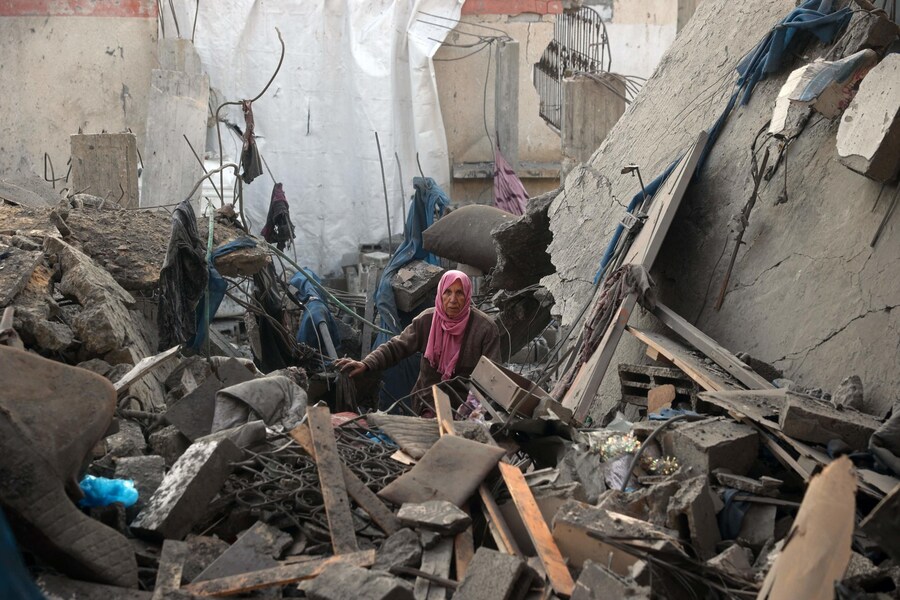 Una donna si trova accanto alle macerie di un edificio distrutto a seguito di un attacco aereo israeliano al campo di rifugiati palestinesi di Bureij, nella Striscia di Gaza centrale. (Eyad BABA / AFP)