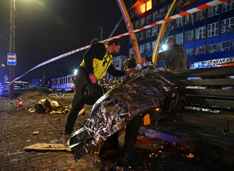 Un agente di polizia ispeziona il corpo di un residente ucciso a una fermata dei mezzi pubblici durante attacchi aerei e missilistici russi, a Zaporizhia. (REUTERS/Stringer) (REUTERS)