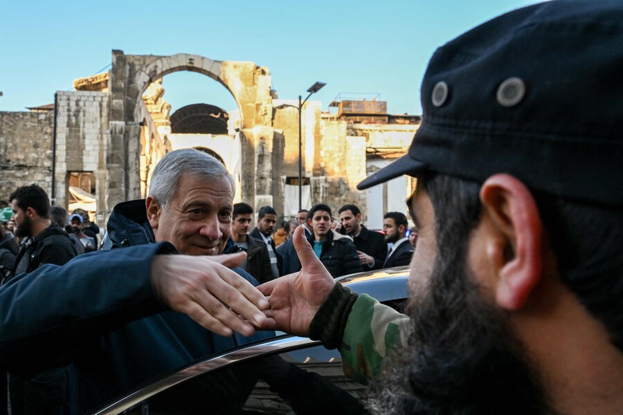 Il ministro degli Esteri italiano Antonio Tajani stringe la mano a un membro delle nuove forze di sicurezza siriane durante la visita alla moschea degli Omayyadi dell’VIII secolo nella città vecchia di Damasco il 10 gennaio 2025 (AFP)