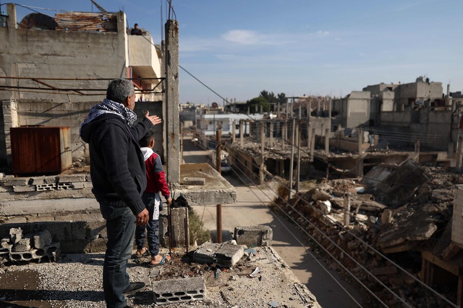 Fayez al-Jammal (2-L), siriano alawita di 46 anni, fuggito in Libano, si trova con uno dei suoi figli sul tetto della sua casa gravemente danneggiata, dopo essere tornato nel quartiere di Baba Amr a Homs. (OMAR HAJ KADOUR / AFP)