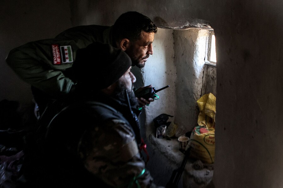 Combattenti della fazione dell’Esercito nazionale siriano sostenuta dalla Turchia guardano da una finestra di una casa in una posizione vicino alla diga di Tishrin. (AAREF WATAD / AFP)