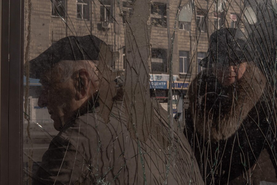 Alcune persone aspettano a una fermata dell’autobus danneggiata in seguito a un recente attacco missilistico russo a Kiev. (Photo by Roman PILIPEY / AFP) (AFP)