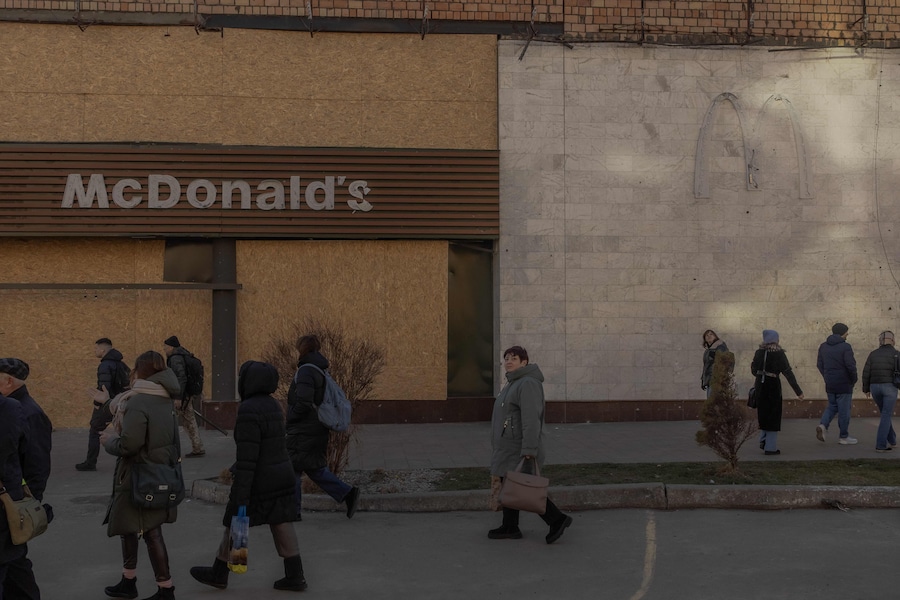 La gente cammina davanti a un McDonald’s danneggiato dopo un recente attacco missilistico russo a Kiev. (Photo by Roman PILIPEY / AFP) (AFP)