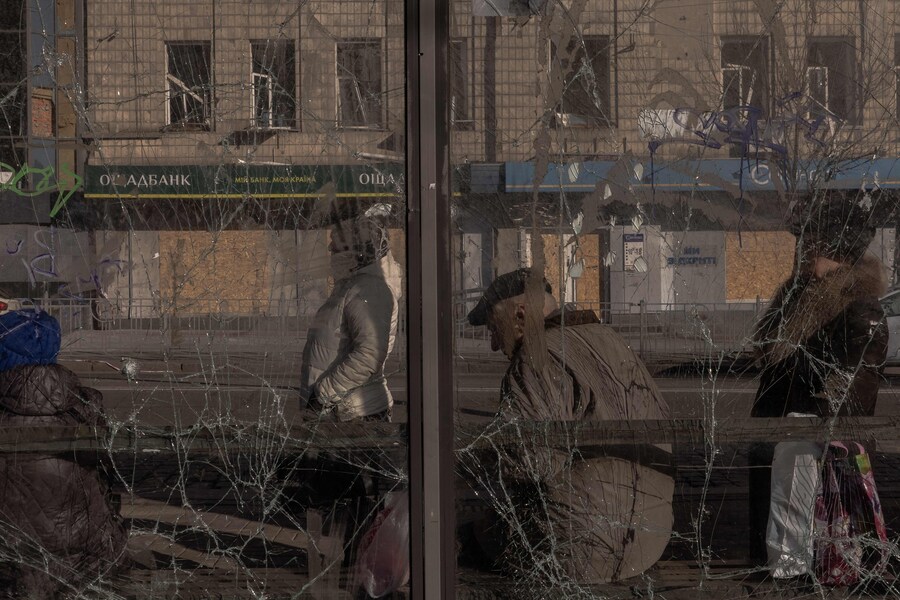 Alcune persone aspettano a una fermata dell’autobus danneggiata in seguito a un recente attacco missilistico russo a Kiev. (Photo by Roman PILIPEY / AFP) (AFP)