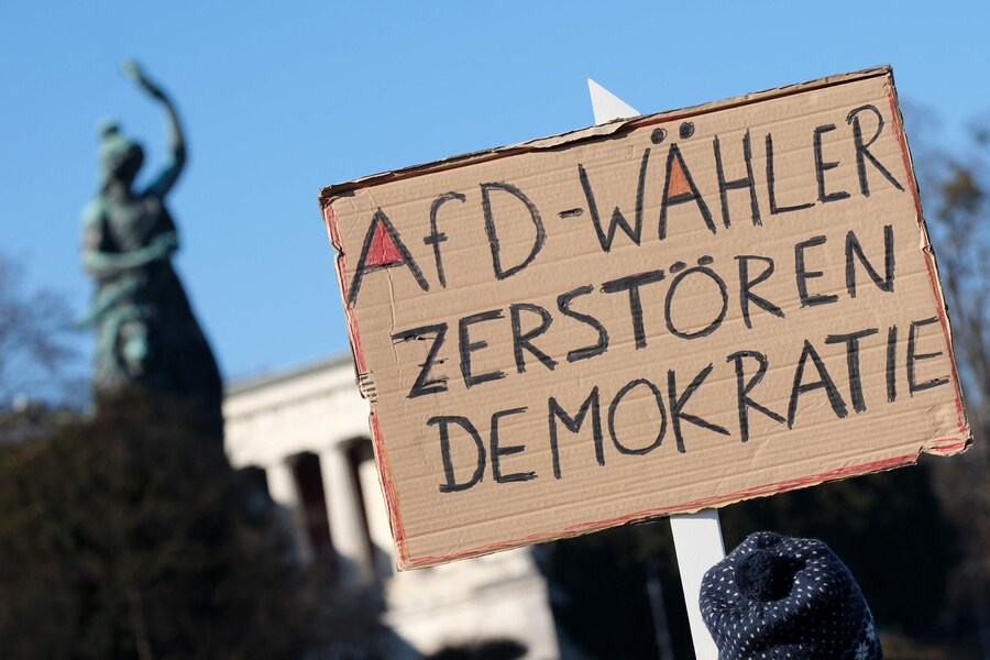 I partecipanti mostrano un cartello con la scritta “Gli elettori dell’AfD distruggono la democrazia” durante una manifestazione contro l’estrema destra al Theresienwiese di Monaco, nel sud della Germania, l’8 febbraio 2025, quasi due settimane prima delle elezioni parlamentari. L’8 febbraio in Germania si sono svolte nuove manifestazioni di massa contro l’estrema destra, tra cui una grandissima mobilitazione a Monaco con 200.000 persone, secondo la polizia della capitale bavarese. (Photo by LUKAS BARTH-TUTTAS / AFP) (AFP)