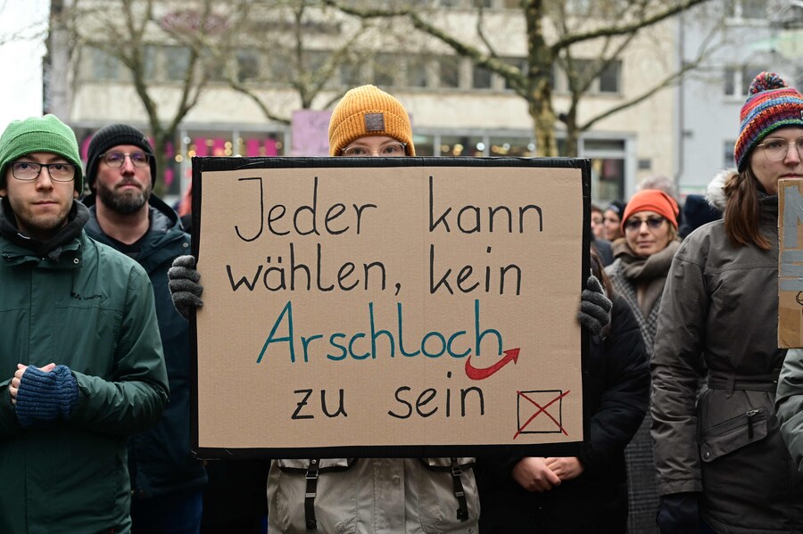 Un manifestante mostra un cartello durante una protesta anti-estrema destra a Dortmund. Molti accusano il centrodestra CDU/CSU, attualmente in testa ai sondaggi con circa il 30%, di aver fatto un buco nel muro la scorsa settimana collaborando con l’AfD per ottenere la maggioranza parlamentare per una risoluzione che chiede un freno all’immigrazione. (Photo by INA FASSBENDER / AFP) (AFP)