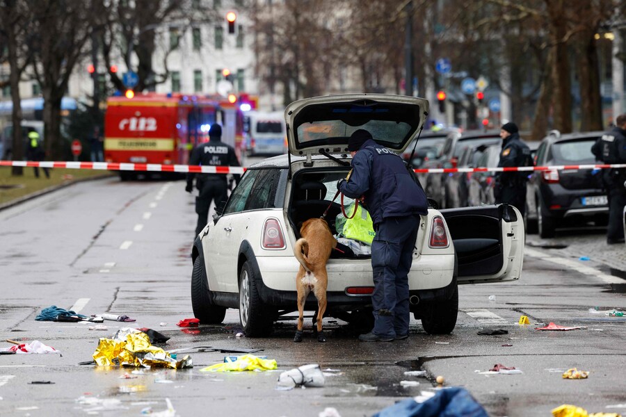 Un agente di polizia usa un cane per perquisire l’auto sulla scena in cui un uomo si è lanciato in mezzo alla folla nella città di Monaco, nel sud della Germania, il 13 febbraio 2025, lasciando diverse persone ferite, ha detto la polizia. La polizia di Monaco ha dichiarato sulla piattaforma social X che “diverse persone sono rimaste ferite” dopo che “un’auto si è schiantata contro un gruppo di persone” nel centro della capitale della Baviera.. (Photo by Michaela STACHE / AFP) (AFP)