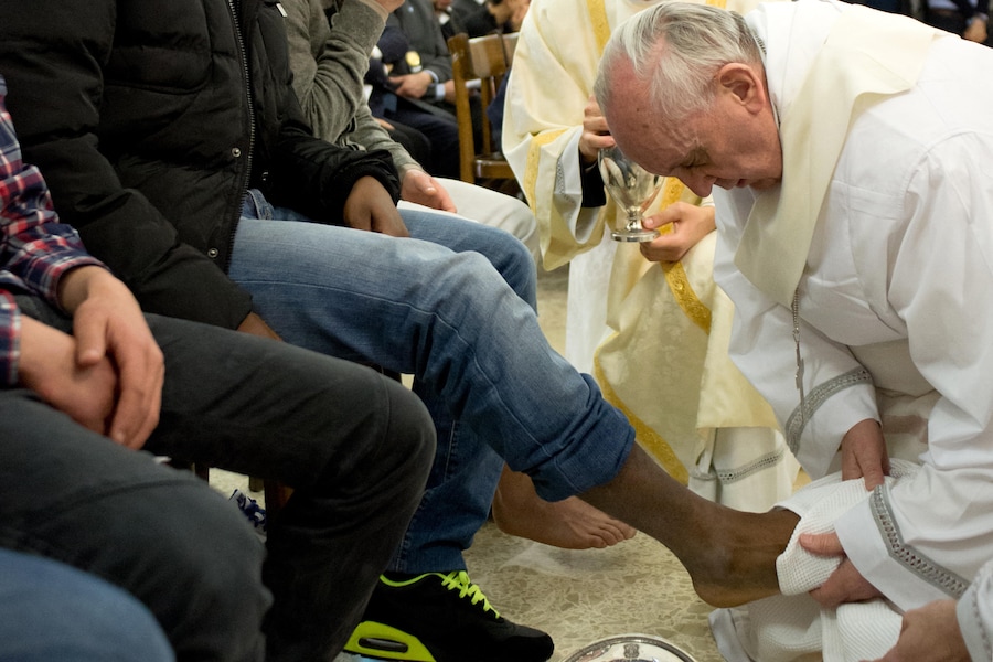 Questa immagine diffusa dalla sala stampa vaticana il 28 marzo 2013 mostra Papa Francesco (a destra) che lava i piedi di un giovane delinquente durante una messa presso la chiesa del carcere giovanile di Casal del Marmo, alla periferia di Roma, nell’ambito del Giovedì Santo. Papa Francesco ha lavato i piedi a 12 giovani delinquenti, tra cui due ragazze, in un carcere di Roma giovedì in una versione senza precedenti di un antico rituale pasquale visto come parte di uno sforzo del nuovo papa per avvicinare la Chiesa cattolica ai bisognosi. (Photo by OSSERVATORE ROMANO / AFP) (AFP)