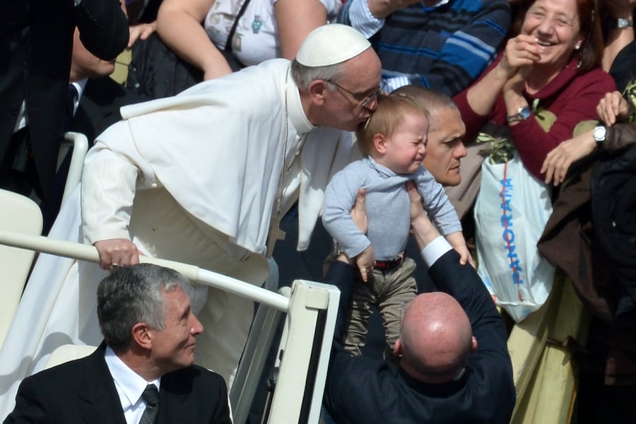 Papa Francesco bacia un bambino mentre se ne va al termine della messa in Piazza San Pietro nell’ambito della celebrazione della Domenica delle Palme, il 24 marzo 2013 in Vaticano. La Domenica delle Palme segna l’inizio della settimana santa di Pasqua in celebrazione della crocifissione e risurrezione di Gesù Cristo. AFP PHOTO / GABRIEL BOUYS (Photo by Gabriel BOUYS / AFP) (AFP)
