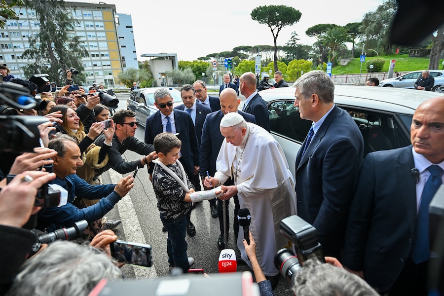 Papa Francesco firma il gesso sul braccio di un bambino all’uscita dall’ospedale Gemelli il 1° aprile 2023 a Roma, dopo essere stato dimesso dopo le cure per una bronchite. Il pontefice, 86 anni, era stato ricoverato all’ospedale Gemelli il 29 marzo dopo aver sofferto di difficoltà respiratorie. (Photo by Filippo MONTEFORTE / AFP) (AFP)