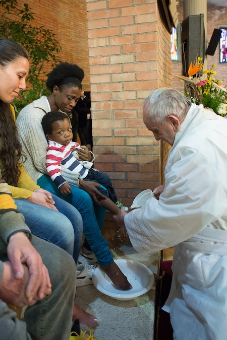 Questa immagine diffusa dalla sala stampa vaticana mostra Papa Francesco che lava i piedi al figlio di una donna detenuta durante una cerimonia nel carcere di Rebibbia a Roma, il Giovedì Santo, il 2 aprile 2015. La tradizionale “lavanda dei piedi”, come fece Gesù per i suoi discepoli, fa parte delle celebrazioni pasquali durante la Settimana Santa. (Photo by OSSERVATORE ROMANO / AFP) (AFP)