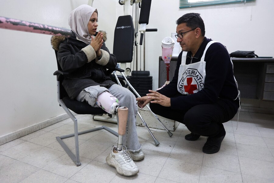 Riham Zarandah, 32 anni, che ha perso una gamba durante un attacco aereo israeliano su Jabalia, nel nord della Striscia di Gaza nel dicembre 2023, parla con un medico della Croce Rossa mentre prova la sua gamba protesica al Gaza Polio and Prosthetics Center di Deir el-Balah. (AFP)
