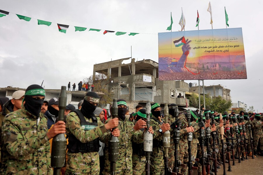 Combattenti e giornalisti di Hamas si riuniscono sul luogo della consegna degli ostaggi israeliani a Rafah, nel sud della Striscia di Gaza, nell’ambito del settimo rilascio di ostaggi e prigionieri, il 22 febbraio 2025. (AFP)