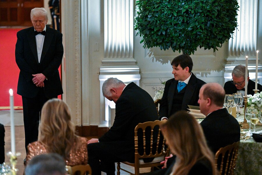Il Presidente degli Stati Uniti Donald Trump (a sinistra) china il capo mentre il Segretario degli Stati Uniti per l’edilizia abitativa e lo sviluppo urbano Scott Turner (fuori dall’inquadratura) prega durante la cena e il ricevimento della National Governors Association nella East Room della Casa Bianca a Washington. (AFP)