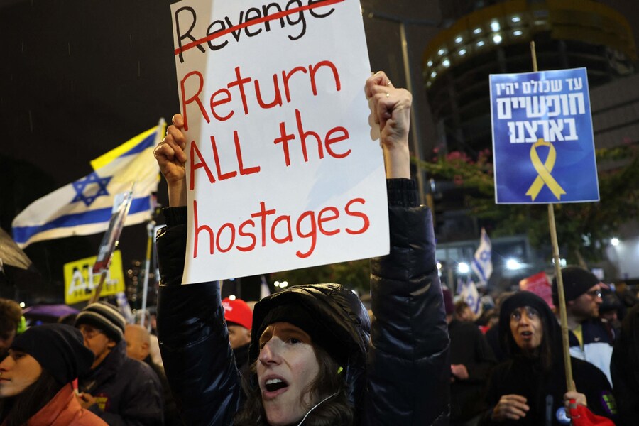 Manifestanti sollevano cartelli e scandiscono slogan durante una protesta che chiede il rilascio degli ostaggi tenuti prigionieri a Gaza, davanti al Ministero della Difesa israeliano a Tel Aviv il 22 febbraio 2025. (AFP)