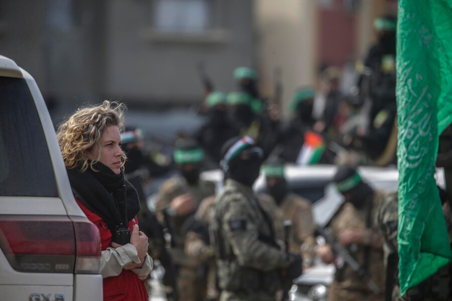 Una rappresentante del Comitato Internazionale della Croce Rossa (CICR) (a sinistra) e alcunimilitanti di Hamas dopo aver firmato i documenti di rilascio di tre ostaggi israeliani nel campo profughi di Al Nusairat, nel centro della Striscia di Gaza, il 22 febbraio 2025. (EPA)
