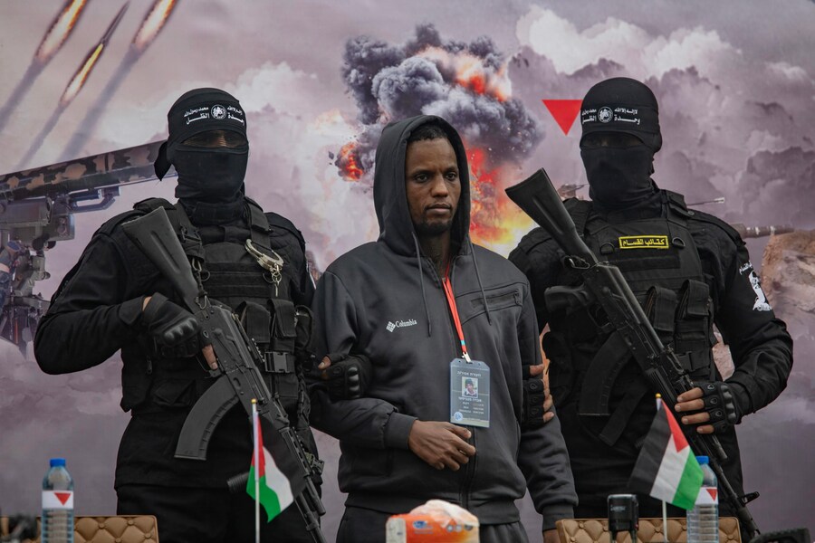 Combattenti delle Brigate Izz ad-Din al-Qassam di Hamas scortano l’ostaggio israeliano Avera Mengistu prima di consegnarlo alla Croce Rossa a Rafah, nel sud della Striscia di Gaza, sabato 22 febbraio 2025. (EPA)