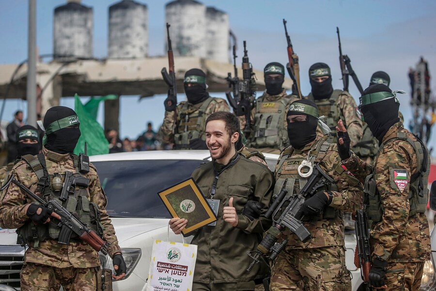 Combattenti delle Brigate Izz ad-Din al-Qassam di Hamas scortano l’ostaggio israeliano Omer Shem Tov prima di consegnarlo alla Croce Rossa nel campo profughi di Al Nusairat, nel centro della Striscia di Gaza, il 22 febbraio 2025. (EPA)