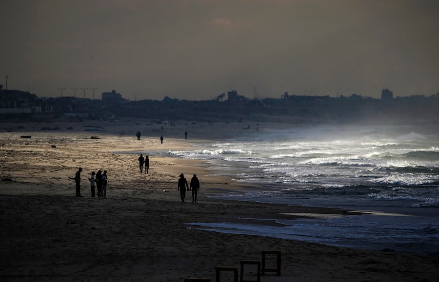 Palestinesi camminano sulla sabbia durante il cessate il fuoco tra Israele e Hamas, nel porto di Gaza, Gaza City. (EPA)