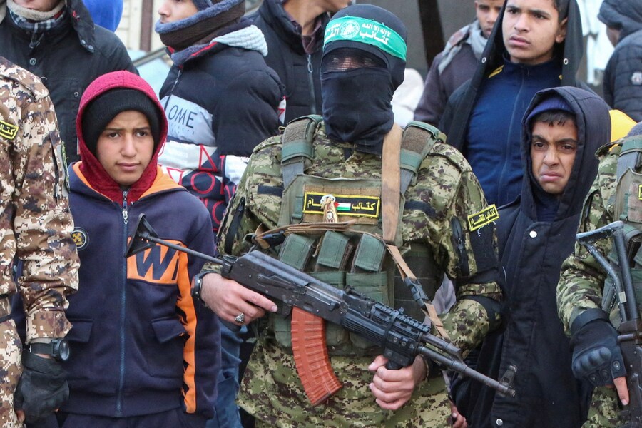 Militanti palestinesi di Hamas fanno la guardia mentre la gente si riunisce nel giorno della consegna degli ostaggi, compresi quelli detenuti a Gaza dal mortale attacco del 7 ottobre 2023, ai membri del Comitato internazionale della Croce Rossa (CICR) come parte del cessate il fuoco e dell’accordo di scambio di ostaggi e prigionieri tra Hamas e Israele, a Rafah. (REUTERS)