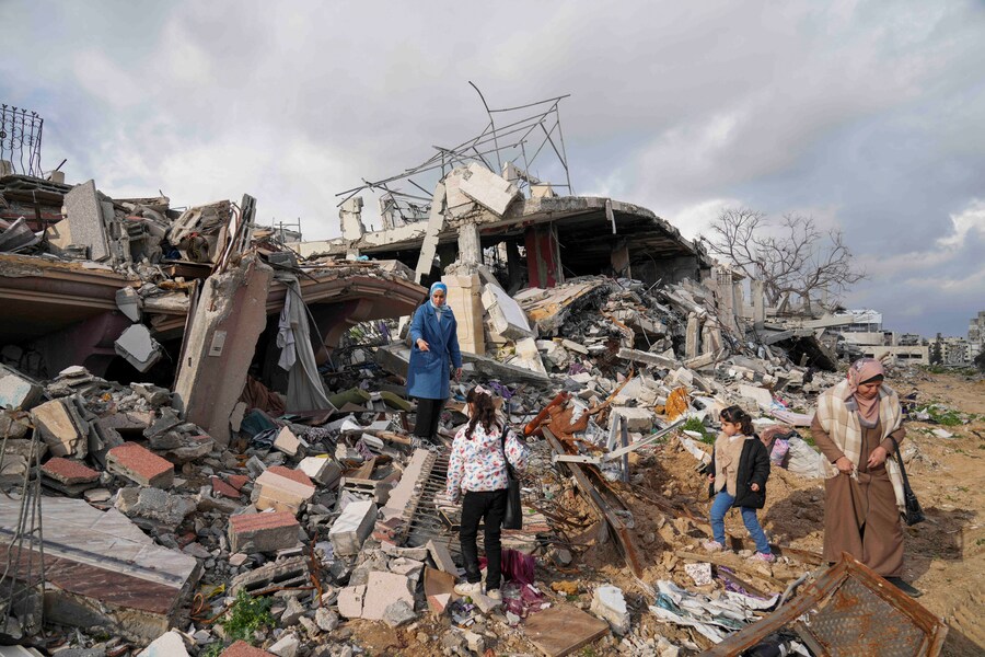 Membri della famiglia Dwaima in piedi sulle macerie della loro casa, rasa al suolo da un attacco aereo israeliano durante la guerra tra Israele e Hamas, nel quartiere di Tal al Hawa a Gaza City. (apn)