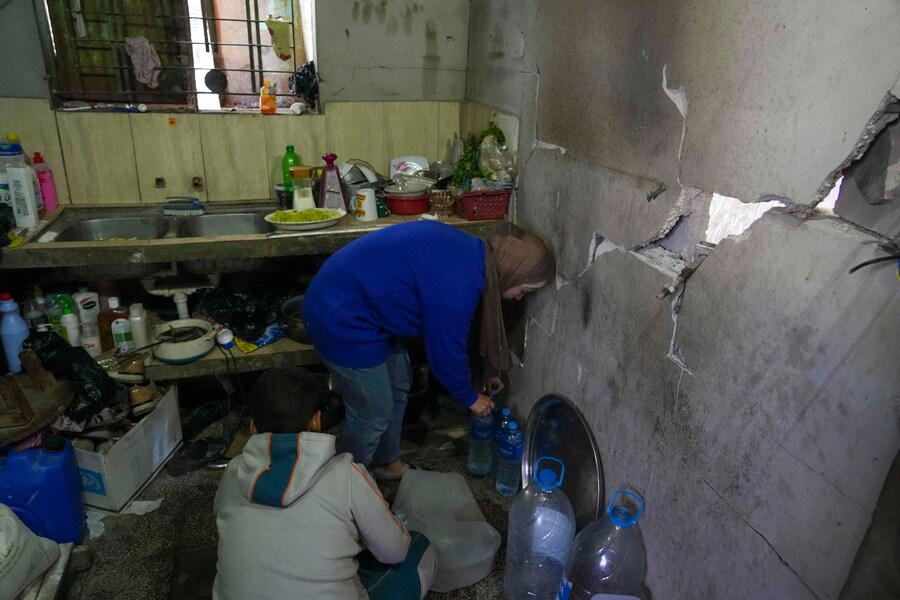 Rawya Tamboura e suo figlio Yazan riempiono bottiglie d’acqua all’interno della loro casa, colpita da un attacco aereo israeliano il 20 ottobre 2023, a Beit Lahiya. (apn)