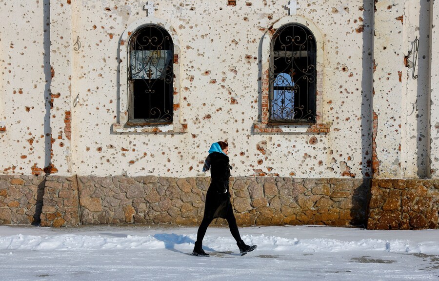 Una donna cammina fuori dal convento di Sant’Ivirone, che è stato gravemente danneggiato dall’artiglieria e dal fuoco delle armi da fuoco durante le battaglie per l’aeroporto locale nel corso del conflitto tra Russia e Ucraina, a Donetsk, una regione dell’Ucraina controllata dalla Russia. (REUTERS/Alexander Ermochenko)