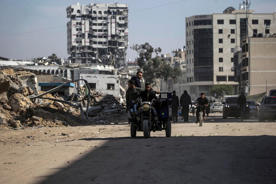 Palestinesi si muovono lungo una strada tra le macerie di edifici distrutti a Gaza City. (EPA)