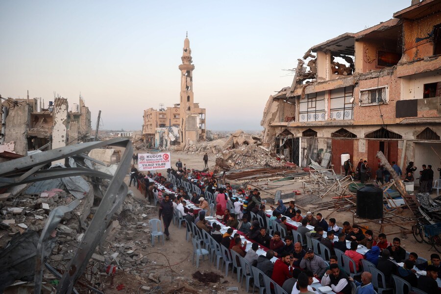 Questa fotografia aerea mostra i palestinesi riuniti per un pasto comune per la rottura del digiuno iftar, tra le devastazioni del campo profughi di Nuseirat, nella Striscia di Gaza centrale. (AFP)