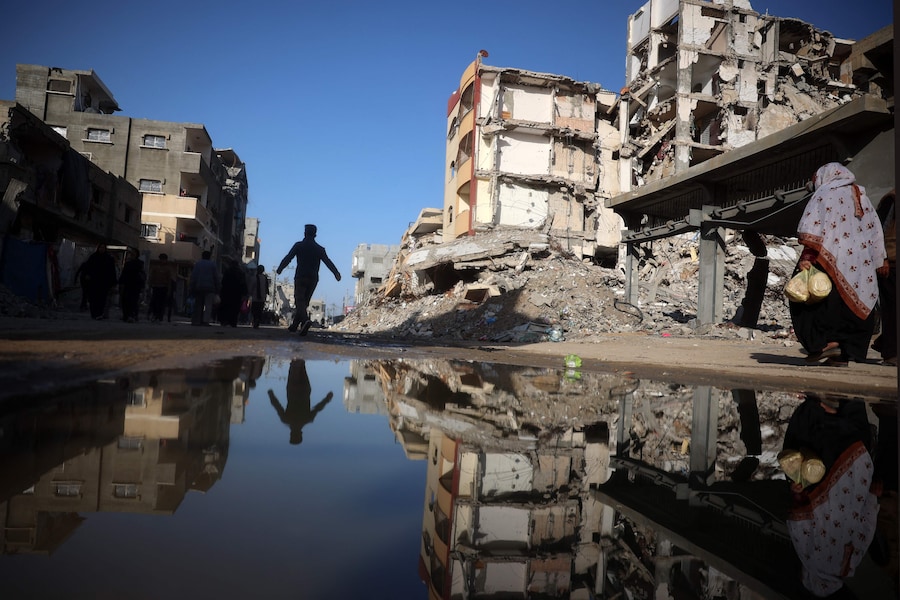 Palestinesi camminano in un quartiere devastato dalla guerra nel campo profughi di Nuseirat. (AFP)