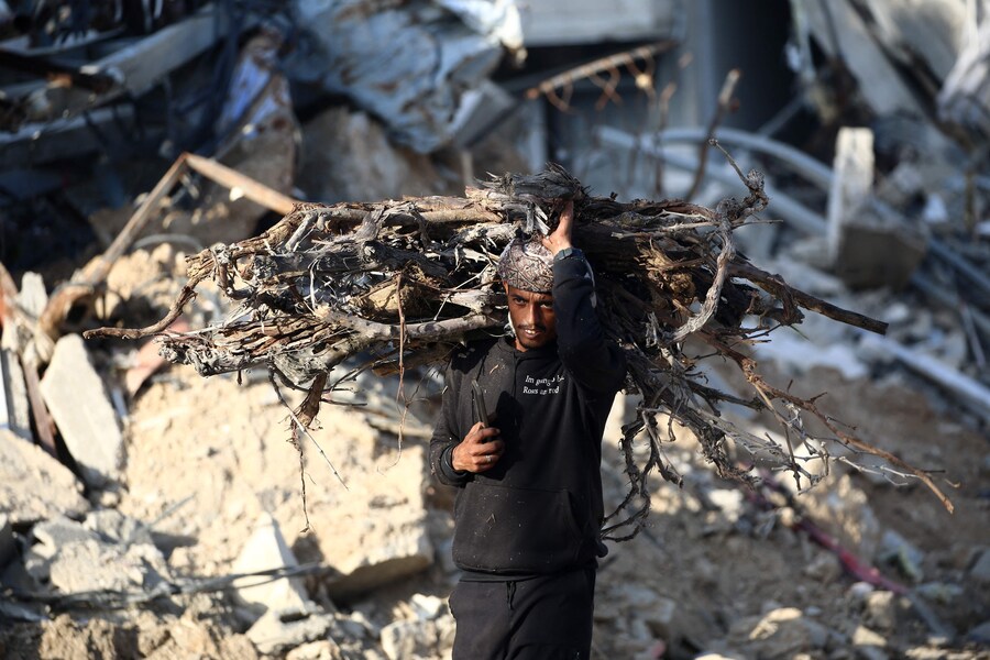 Un uomo palestinese trasporta ramoscelli da usare per cucinare nel campo profughi di Nuseirat, nella Striscia di Gaza centrale. (AFP)
