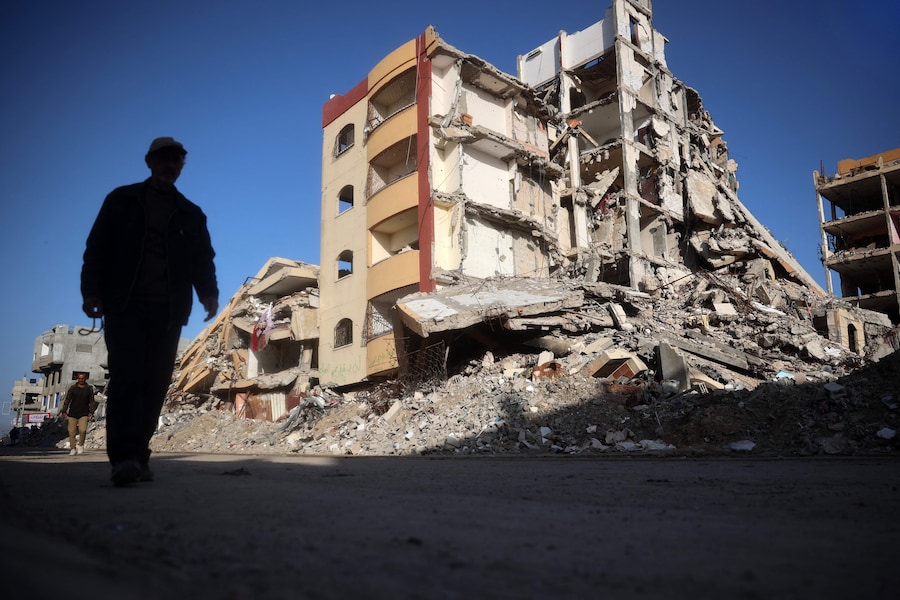Palestinesi camminano in un quartiere devastato dalla guerra nel campo profughi di Nuseirat, nella Striscia di Gaza centrale. (AFP)