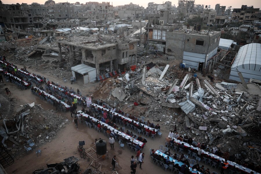 Questa fotografia aerea mostra i palestinesi riuniti per un pasto comune per la rottura del digiuno iftar, tra le devastazioni del campo profughi di Nuseirat, nella Striscia di Gaza centrale. (AFP)