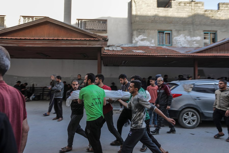 Persone trasportano il corpo coperto di un giovane palestinese ucciso a seguito di un attacco aereo israeliano nel quartiere di Al Zaytoun, a est di Gaza City,. (EPA)