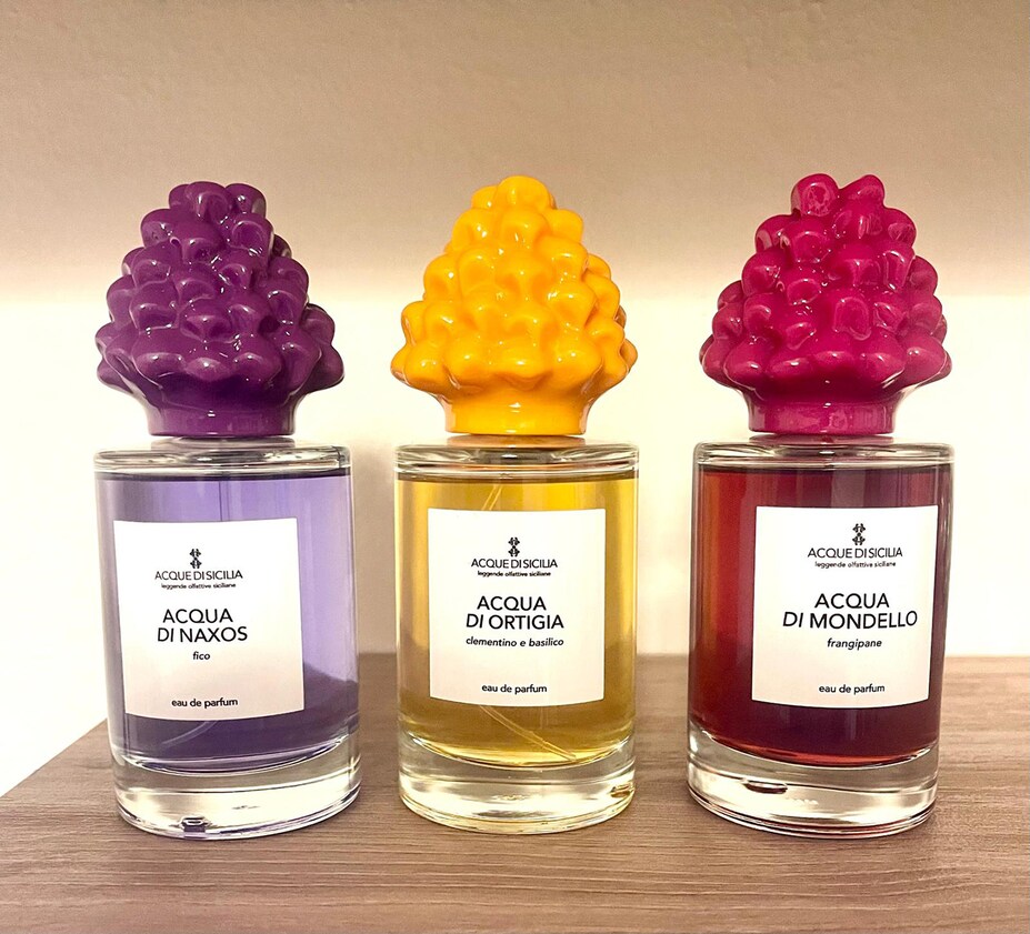 SIKELIA PARFUMS. Acque di Sicilia. Un tributo alla Sicilia attraverso il linguaggio della profumeria artistica. La collezione Acque di Sicilia celebra l’isola con tre fragranze ispirate ai suoi paesaggi e alle sue materie prime . Acqua di Naxos, con il fico come protagonista, Acqua di Ortigia, un vibrante connubio di clementino e basilico e Acqua di Mondello, dominata dal frangipane, evoca la sensualità floreale e solare delle spiagge palermitane. Ogni flacone è impreziosito da un tappo in ceramica ispirato alla tradizione siciliana delle pigne decorative, simbolo di prosperità e buon auspicio.