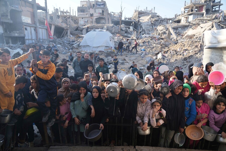 I palestinesi aspettano il cibo donato in un centro di distribuzione a Beit Lahiya, nella Striscia di Gaza settentrionale. (AP Photo/Abdel Kareem Hana) (APN)