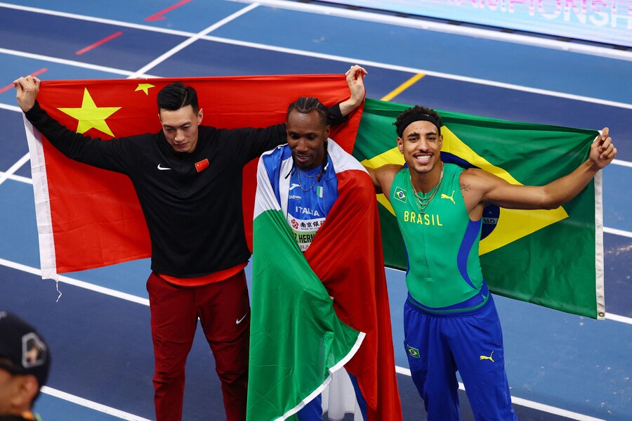 Nanjing Youth Olympic Sports Park, Nanjing, Cina - 21 marzo 2025 L’italiano Andy Diaz Hernandez festeggia la vittoria nel salto triplo maschile insieme al cinese Yaming Zhu, secondo classificato, e al brasiliano Almir Dos Santos, terzo classificato (REUTERS/Issei Kato) (REUTERS)