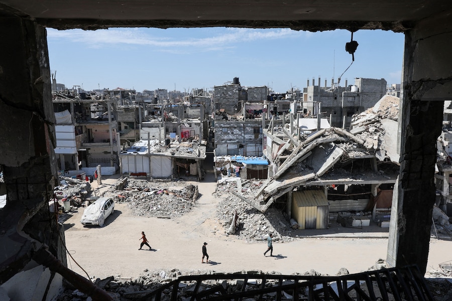 Palestinesi camminano vicino alle macerie delle case a Khan Younis, nella Striscia di Gaza meridionale. REUTERS/Ramadan Abed (REUTERS)