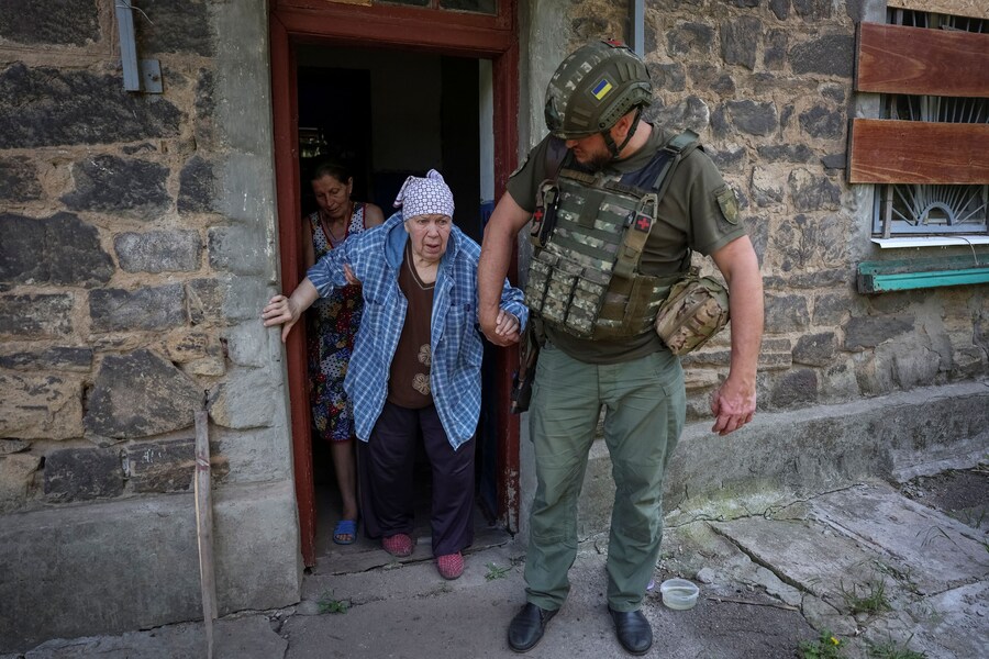 Un agente di polizia evacua un’anziana donna dalla sua casa nella città di Kostyantynivka, in prima linea, nella regione di Donetsk, Ucraina (REUTERS)