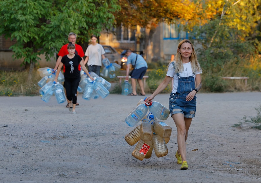 Residenti locali camminano per raccogliere l'acqua consegnata da un camion cisterna nel corso del conflitto militare tra Russia e Ucraina, a Donetsk, città ucraina controllata dai russi. (REUTERS/Alexander Ermochenko)