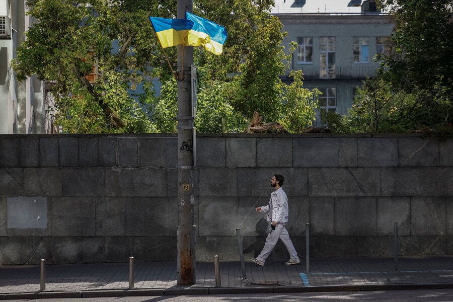 Un uomo passa accanto alle bandiere ucraine nel Giorno della Bandiera di Stato, in occasione dell'invasione russa, nel centro di Kiev, Ucraina, il 23 agosto 2025. (REUTERS/Alina Smutko)