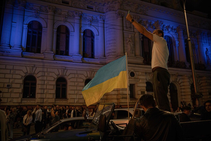 Un uomo scatta una fotografia accanto a una bandiera ucraina durante le celebrazioni del Giorno dell'Indipendenza, nel centro di Kharkiv, il 24 agosto 2025. (AFP)