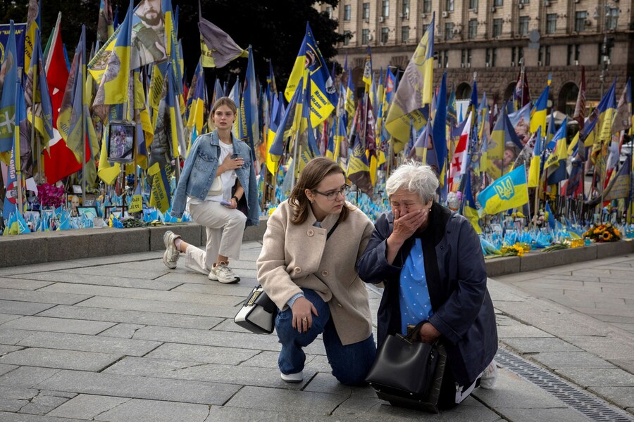 I passanti si inginocchiano per rendere omaggio a un soldato ucraino caduto mentre assistono al suo corteo funebre in Piazza Indipendenza, Kiev, Ucraina, 25 agosto 2025. (REUTERS)