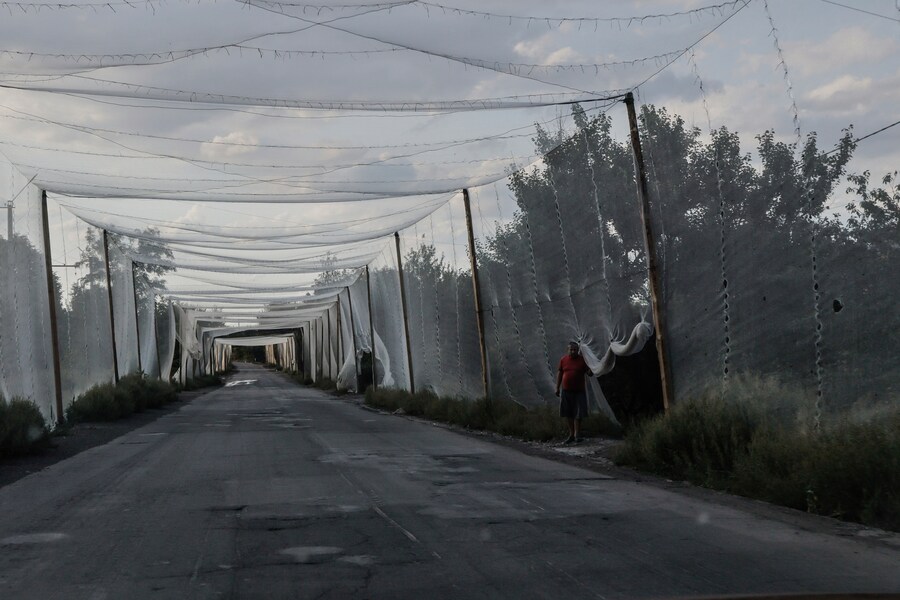 Un residente attraversa la strada sotto una rete anti droni nella città di Kostiantynivka, nella regione di Donetsk, Ucraina, domenica 24 agosto 2025. (APN)