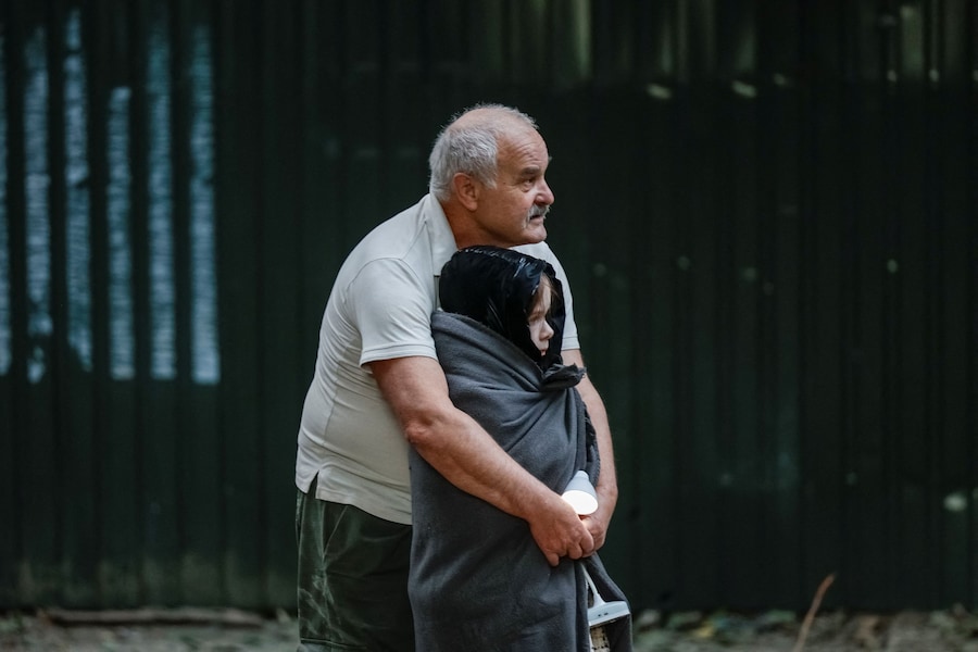 Un uomo abbraccia un bambino davanti agli edifici colpiti dai missili e dai droni russi, Kiev, Ucraina, 28 agosto 2025. (REUTERS)