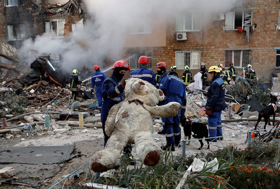 Un soccorritore tiene in mano un peluche davanti a un edificio colpito da missili e droni russi a Kiev, in Ucraina, il 28 agosto 2025. (REUTERS)