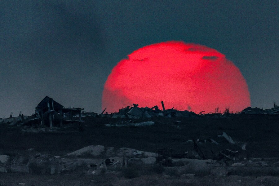 Questa foto, scattata da una postazione al confine israeliano con la Striscia di Gaza, mostra il sole che tramonta dietro gli edifici distrutti nel territorio in difficoltà, il 27 agosto 2025, nel corso della guerra in corso tra Israele e il gruppo militante palestinese Hamas. Un portavoce dell'esercito israeliano ha dichiarato mercoledì che l'evacuazione di Gaza City è "inevitabile", poiché l'esercito si prepara a conquistare la città più grande del territorio palestinese. (Foto di Jack GUEZ / AFP) (AFP)