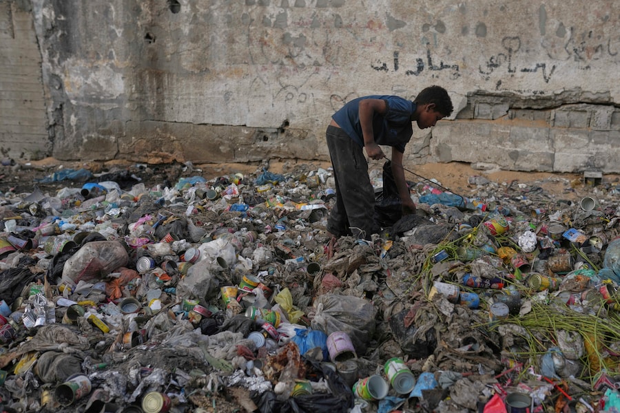 Yassin Al-Masry, 13 anni, fruga tra i rifiuti alla ricerca di plastica da usare per preparare il fuoco per cucinare, a Gaza City. (Foto AP/Jehad Alshrafi) (APN)